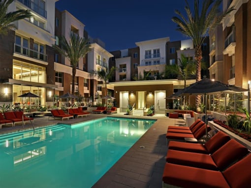 A swimming pool surrounded by red chairs and umbrellas at a resort at West Park Apartments, California, 92108