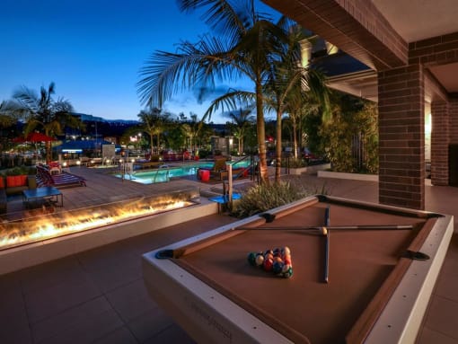 A pool table is set up on a patio with a pool table cloth and balls on it at West Park Apartments, San Diego, California