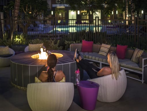 Two women sitting on a couch and a table with a lit candle in the middle at West Park Apartments, San Diego, CA