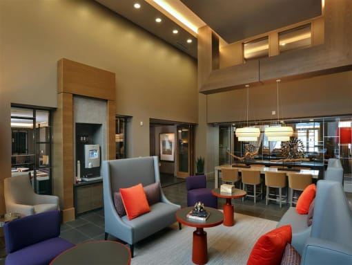 A modern living room with a grey sofa, a purple armchair, and a red pillow at West Park Apartments, San Diego