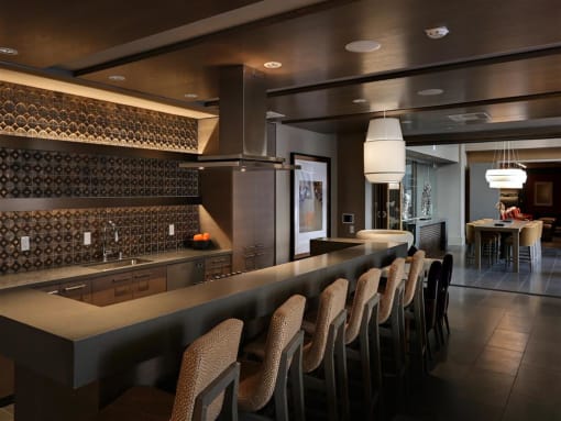 A modern kitchen with a bar area and chairs at West Park Apartments, California