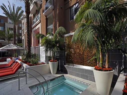 A pool surrounded by plants and a red bench at West Park Apartments, California