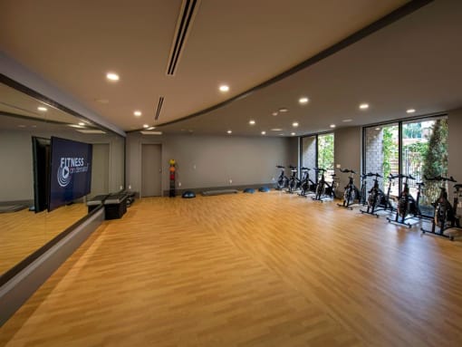 A gym with wooden floors and exercise bikes at West Park Apartments, California, 92108