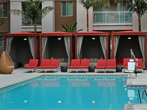 A pool with red chairs and a canopy at West Park Apartments, California, 92108