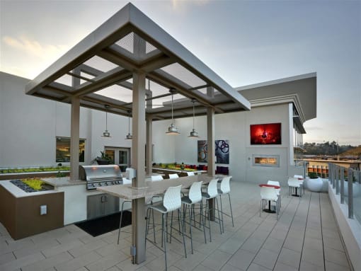A modern outdoor kitchen with a dining table and chairs at West Park Apartments, San Diego, 92108