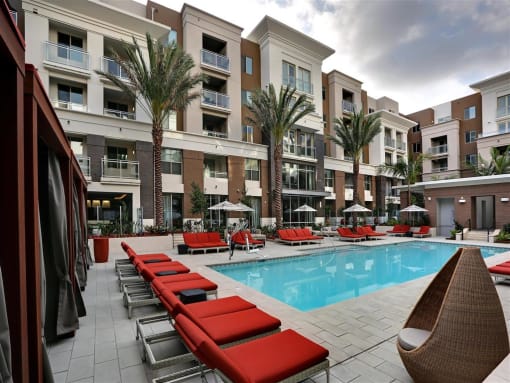 A pool area with red sun loungers and a white chair at West Park Apartments, San Diego, California