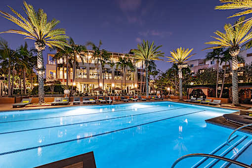 A large swimming pool surrounded by palm trees at night.