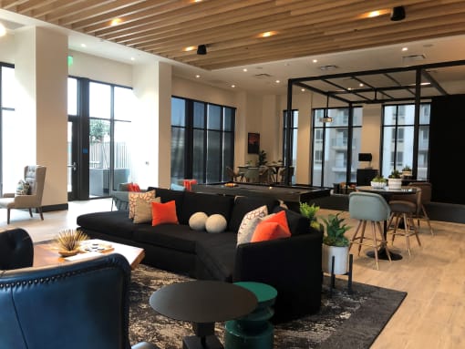 A black couch with orange and white pillows sits in a modern living room at Purl Apartments, San Diego