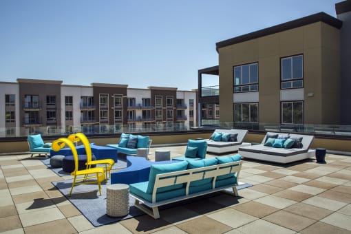 A sunny day at a modern outdoor seating area with blue and yellow chairs at Purl Apartments, California