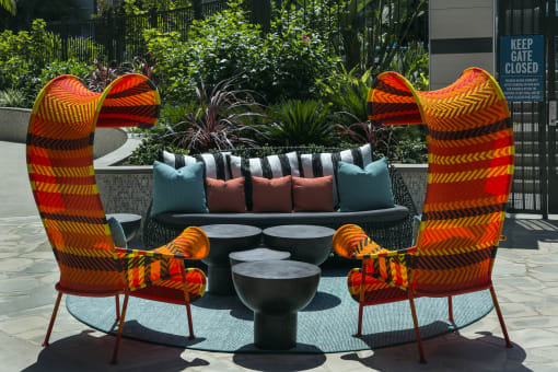 A set of four chairs with orange and black striped cushions are arranged around a table at Purl Apartments, San Diego, CA