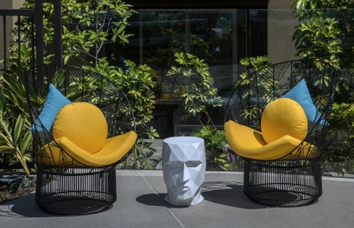 Two yellow chairs with blue pillows are placed outside at Purl Apartments, San Diego, CA