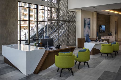 A reception area with a white reception desk and green chairs at Purl Apartments, San Diego