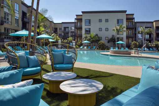 A pool area with blue chairs and a yellow table at Purl Apartments, San Diego, California