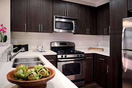 A modern kitchen with dark brown cabinets and stainless steel appliances at Circa 37 Apartments, California, 92108