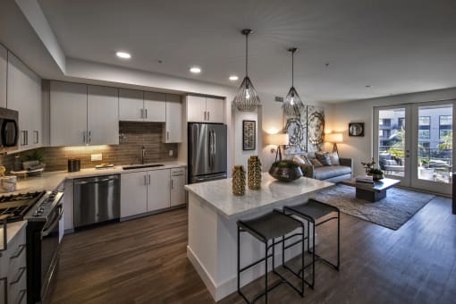 A modern kitchen with a bar area and a view of the city at Purl Apartments, California