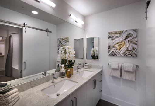 A bathroom with a sink, mirror, and towel rack at Purl Apartments, San Diego