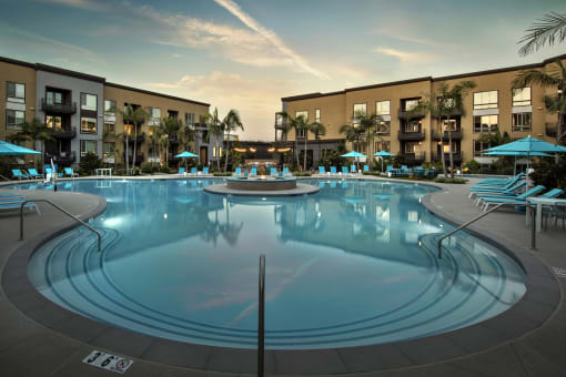A large outdoor swimming pool surrounded by lounge chairs and umbrellas at Purl Apartments, San Diego