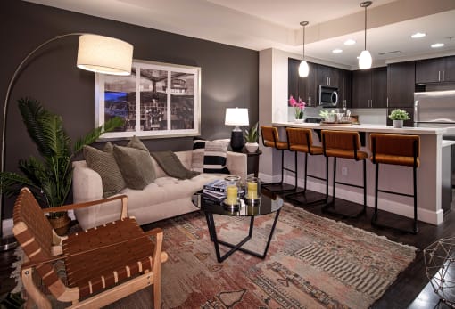 A modern living room with a white sofa, a wooden chair, and a coffee table. at Circa 37 Apartments, San Diego, 92108