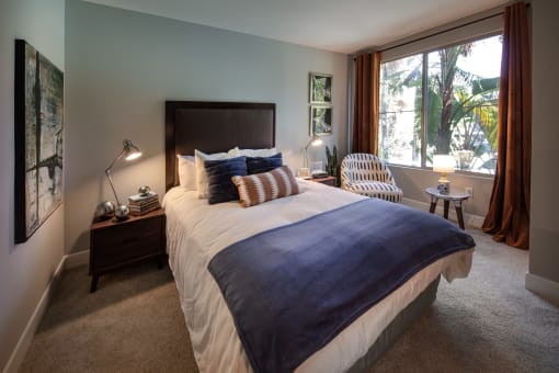 A bedroom with a large bed and a window with curtains. at Circa 37 Apartments, San Diego, CA, 92108