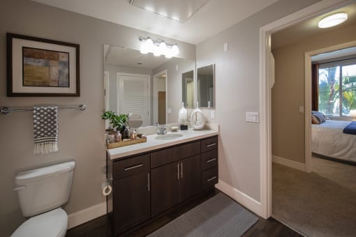 A bathroom with a toilet, sink, and mirror. at Circa 37 Apartments, California