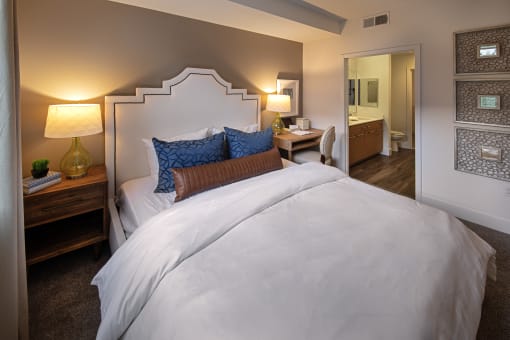 A bedroom with a large bed and a nightstand with a lamp at West Park Apartments, California