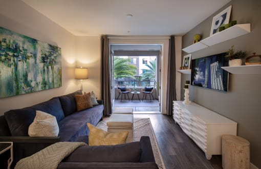 A living room with a blue couch and a painting on the wall at West Park Apartments, San Diego, California
