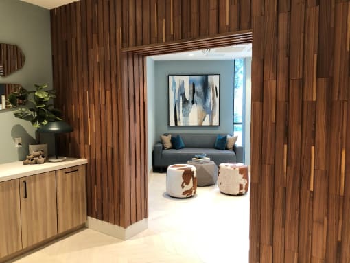 A modern living room with wooden paneling and a grey couch at Purl Apartments, San Diego, CA