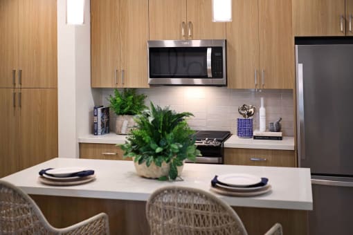 a kitchen with a counter and a table with chairs at Luma at El Corazon Apartments, Oceanside, CA 92056