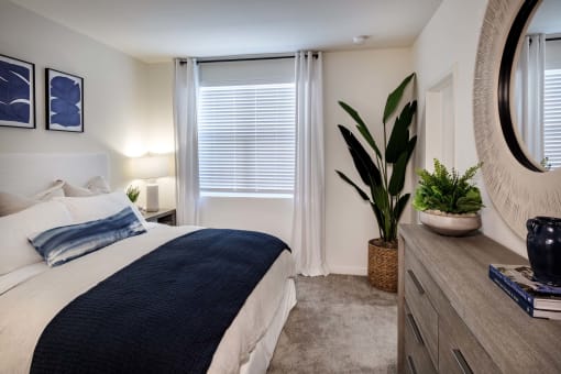 a bedroom with a bed and a potted plant at Luma at El Corazon Apartments, Oceanside