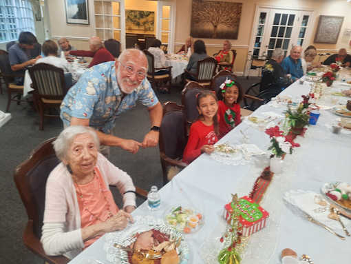 A group of people are sitting around a long table with a festive meal  at Savannah Grand of Sarasota, Sarasota, 34238.
