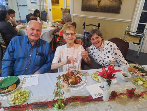 Three people sitting at a table with plates of food in front of them  at Savannah Grand of Sarasota, Sarasota, FL.