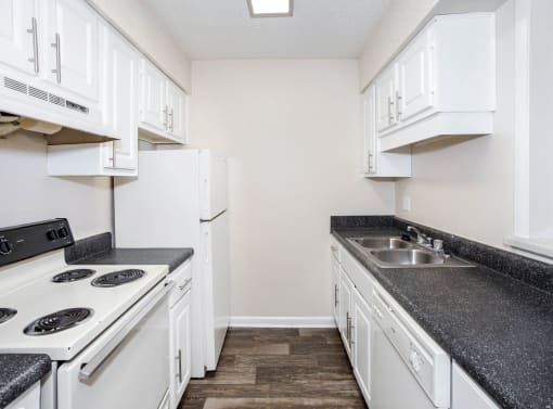 a kitchen with white appliances and black counter tops and white cabinets