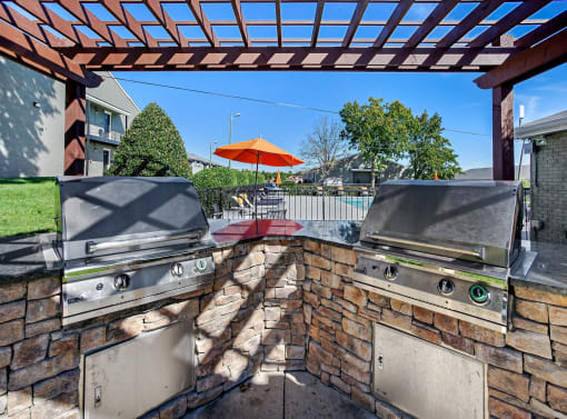 the backyard has a grill and barbecue area and a patio with umbrellas