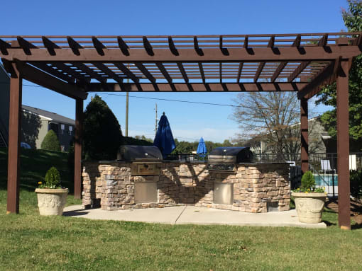 a stone patio with a grill and a pergola