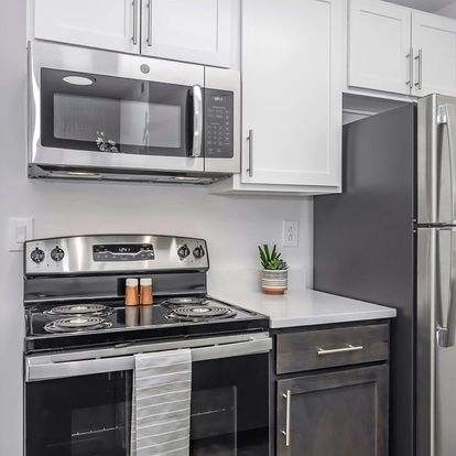 A modern kitchen with a stainless steel oven and microwave above a stove.