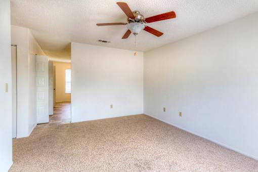 A room with a ceiling fan and carpeted floor.