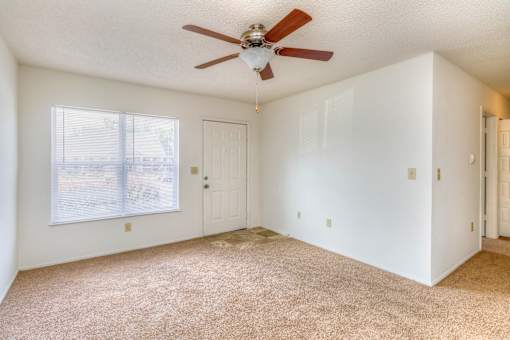 A room with a ceiling fan and carpeted floor.