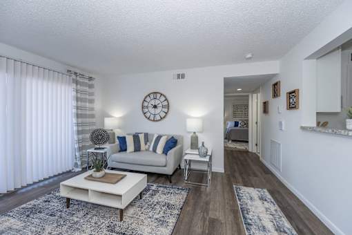 A living room with a white couch and a clock on the wall.
