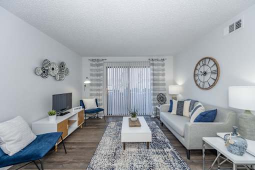A living room with a white couch, blue chairs, and a rug.