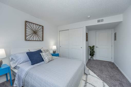 A bedroom with a bed, nightstands, and a door.