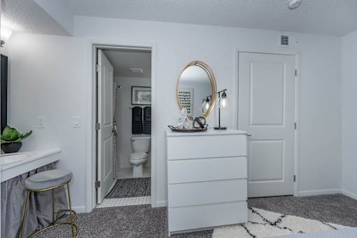 A bathroom with a white vanity and a round mirror.