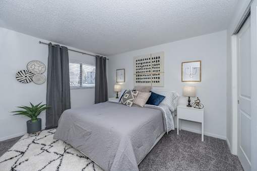 A bedroom with a bed, nightstand, and a wall hanging.