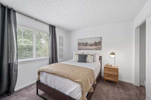 A bedroom with a large bed and a painting on the wall.
