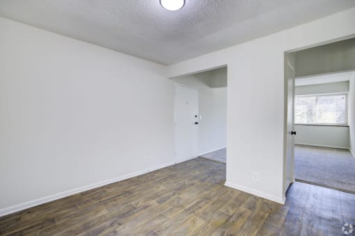 an empty living room with white walls and wood flooring
