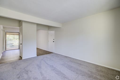 an empty living room with white walls and carpet