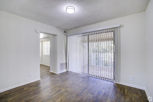 the living room of an apartment with wood flooring and a sliding glass door