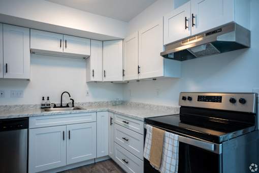 a kitchen with white cabinets and black appliances and a sink