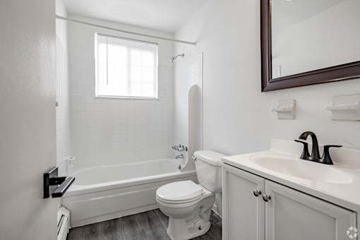 A white bathroom with a toilet, sink, and bathtub.