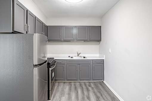 A kitchen with a refrigerator, sink, and cabinets.