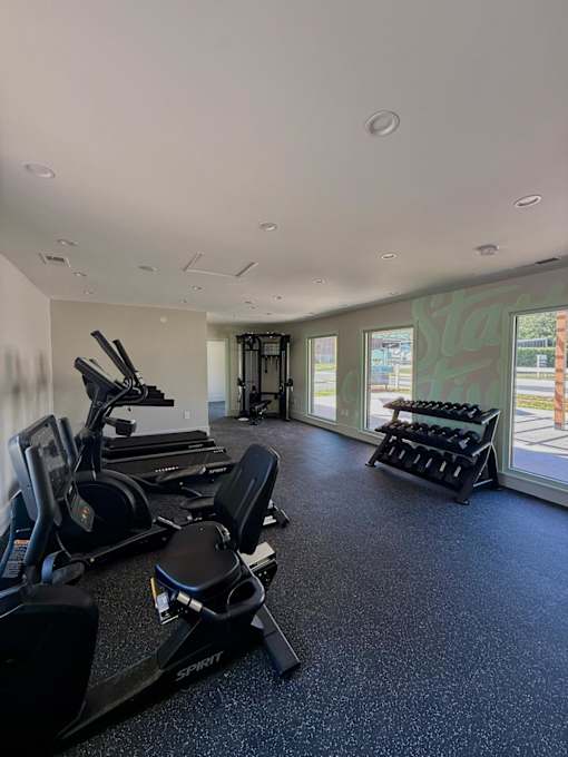 A gym with treadmills, exercise bikes, and dumbbells.